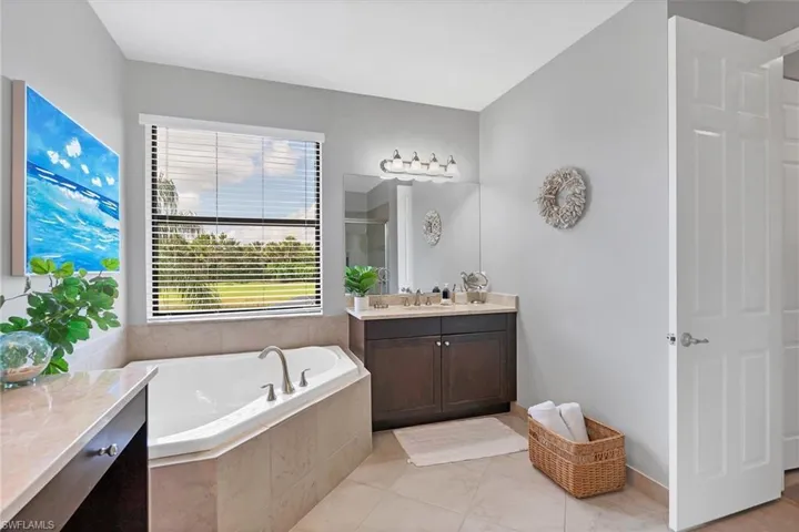 Bathroom featuring tile flooring, a relaxing tiled bath, and vanity with extensive cabinet space