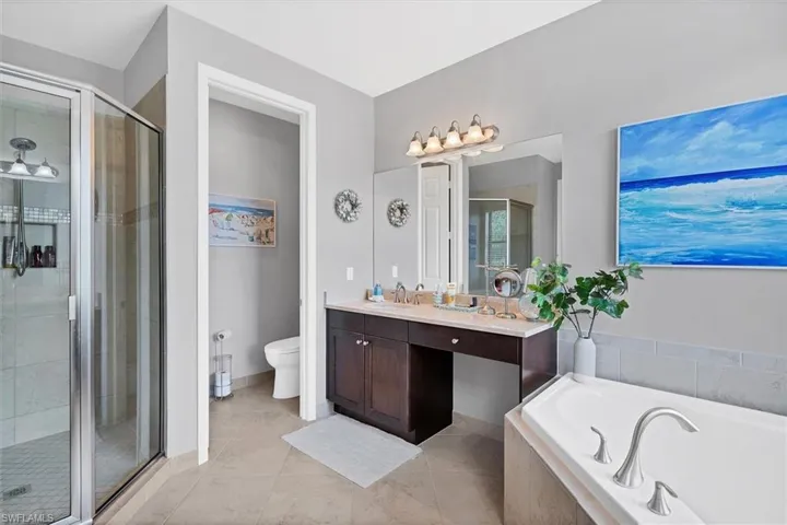 Full bathroom with tile floors, shower with separate bathtub, oversized vanity, and toilet