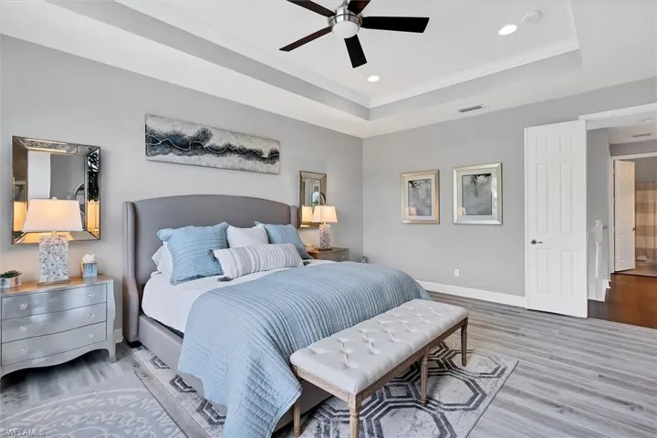 Bedroom with ceiling fan, a tray ceiling, crown molding, and hardwood / wood-style flooring