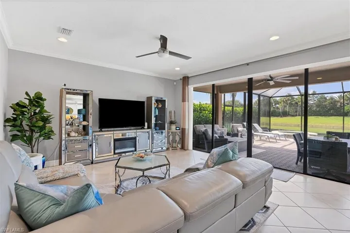 Living room with ornamental molding, ceiling fan, and light tile floors