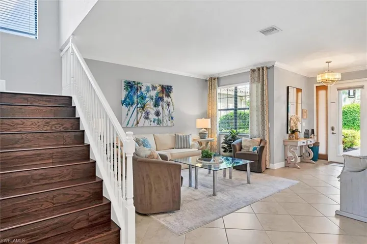 Tiled living room featuring a notable chandelier and ornamental molding