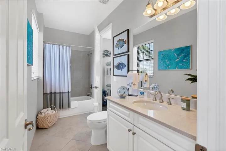 Full bathroom with shower / bath combo with shower curtain, oversized vanity, tile flooring, and toilet
