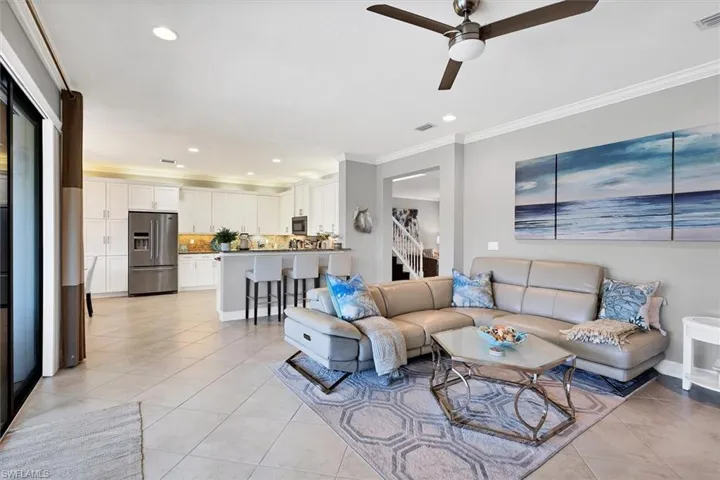 Living room with ornamental molding, light tile flooring, and ceiling fan