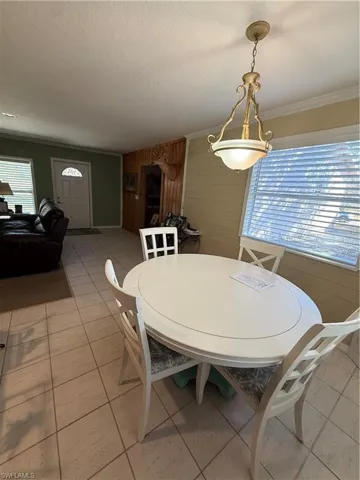 Dining space featuring wooden walls, light tile patterned floors, a textured ceiling, and crown molding