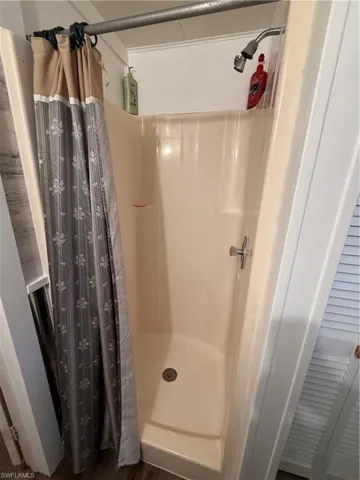 Full bathroom featuring a shower stall and dark wood-type flooring
