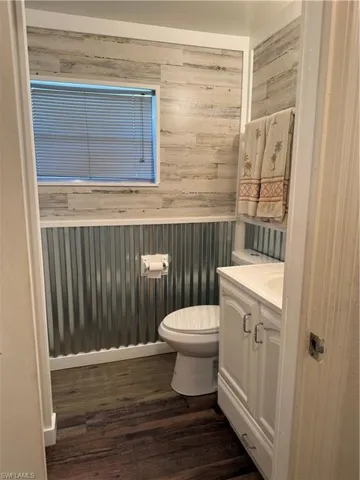 Bathroom with vanity, wooden walls, and dark wood-style floors
