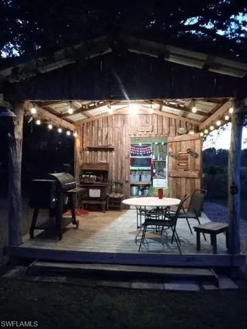 Patio at night featuring a deck, a grill, and outdoor dining space