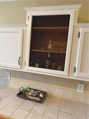 Kitchen view of a textured wall, white cabinets, and tile countertops