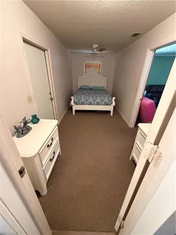 Bedroom with a textured ceiling, carpet, and ceiling fan