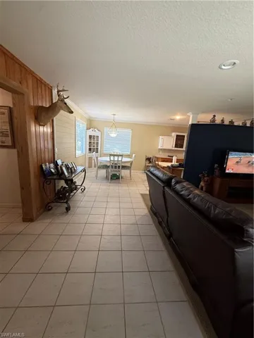 Living room featuring wooden walls, a textured ceiling, and light tile patterned floors