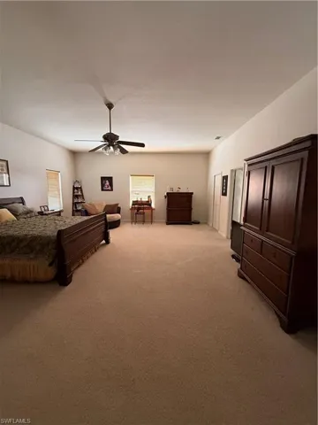 Bedroom with light colored carpet and a ceiling fan