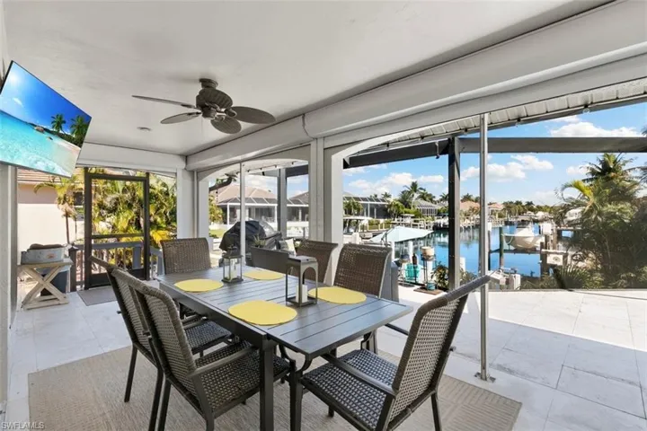 Sunroom featuring a water view, a ceiling fan, outdoor dining area, and a patio