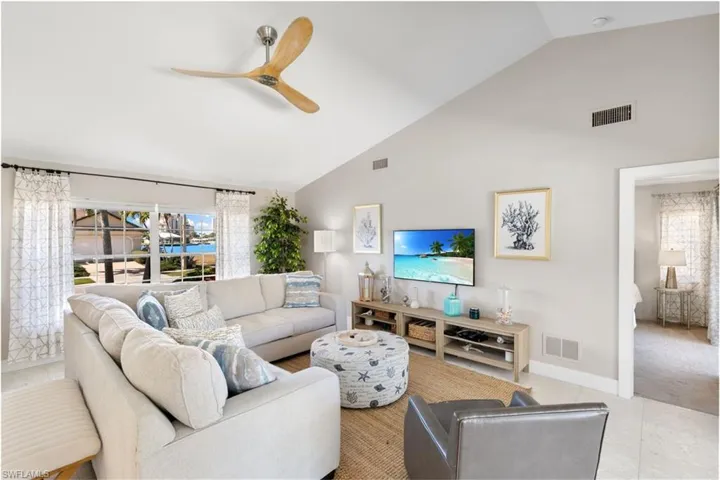 Living room featuring vaulted ceiling, ceiling fan, and tile patterned floors