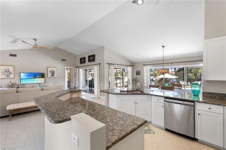 Kitchen with white cabinets, dark stone countertops, dishwasher, open floor plan, and ceiling fan