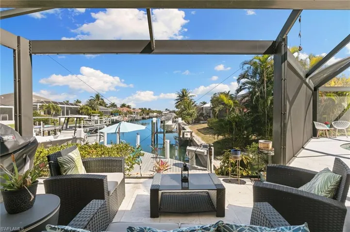View of patio with a boat dock, a water view, grilling area, an outdoor lounge area, and a sunroom