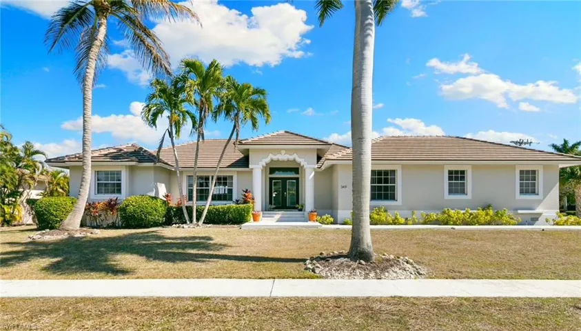 View of front of property featuring a front lawn, stucco siding, french doors, and a tile roof