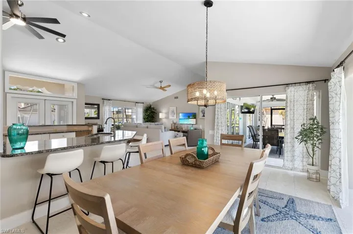 Dining space with a ceiling fan, suspended lighting, and lofted ceiling