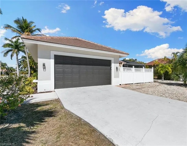 View of front of property with a garage, a tiled roof, stucco siding, and concrete driveway