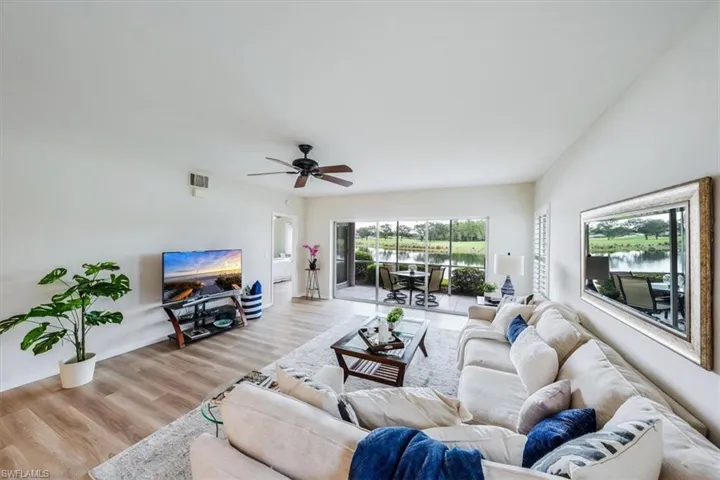 Living room with a water view, ceiling fan, and light wood-type flooring
