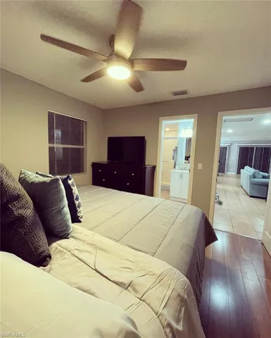 Bedroom featuring a textured ceiling, wood finished floors, a ceiling fan, and connected bathroom