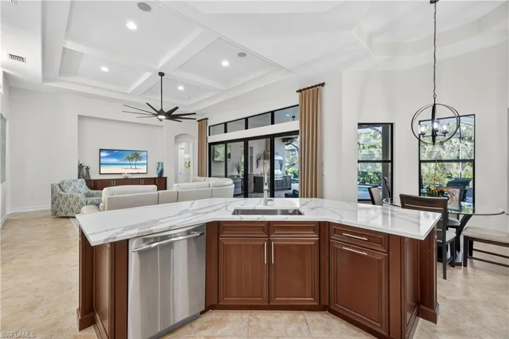 Open Kitchen Featuring Stainless Steel Dishwasher, a Center Island with Sink, Coffered Ceiling, and Upgraded Ceiling Fan, and Breakfast Nook