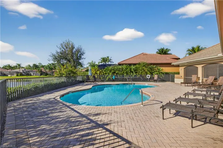 Black Bear Ridge Community Heated Pool Overlooking the Lake, Lounge Chairs, Umbrella's Rolling Out for Season, and Screened Lanais with Tables and Chairsfeaturing a patio area