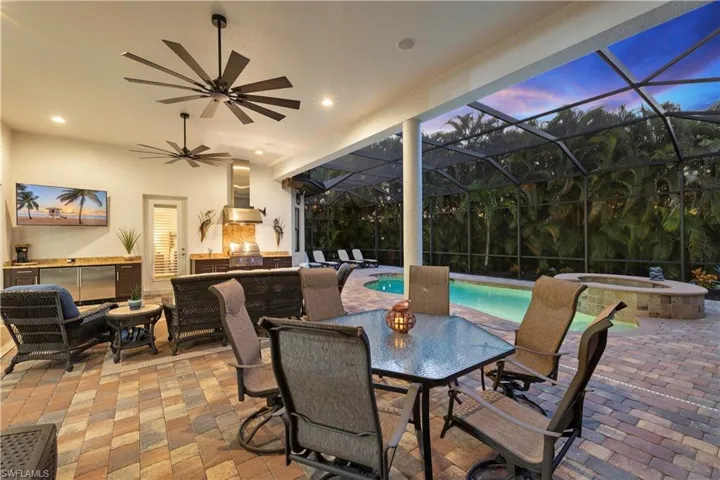 Screened Lanai at Dusk Featuring Outdoor Dining and Entertaining Area, Screened enclosure, Upgraded Ceiling Fans, and Heated Saltwater Pool and Spa