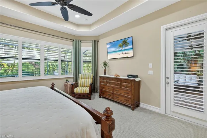 Primarty Bedroom with Carpet Overlooking Screened Lanai, Tray ceiling, Ceiling Fan, Plantation Shutters, and Private Door to Screened Lanai
