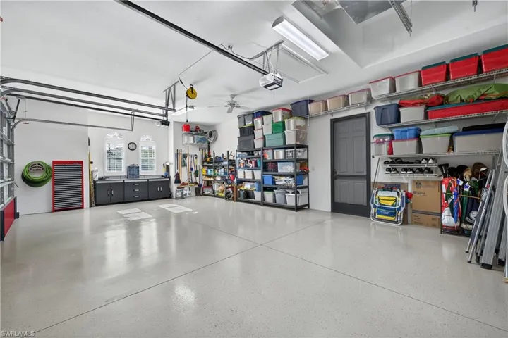 3 Car Garage Featuring Epoxy Coated Floor, Ceiling fan, Workshop/Bench, Ample Storage, Screen Door Added to Pedestrian Door, and Garage Door Opener