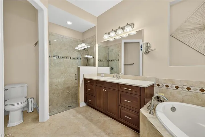 Primary Bathroom Ensuite with a Walk-In Glass Shower with Two Shower Heads, Dual Vanities, a Soaking Tub.  Door can be Re-Installed to Toilet Area if Desired.