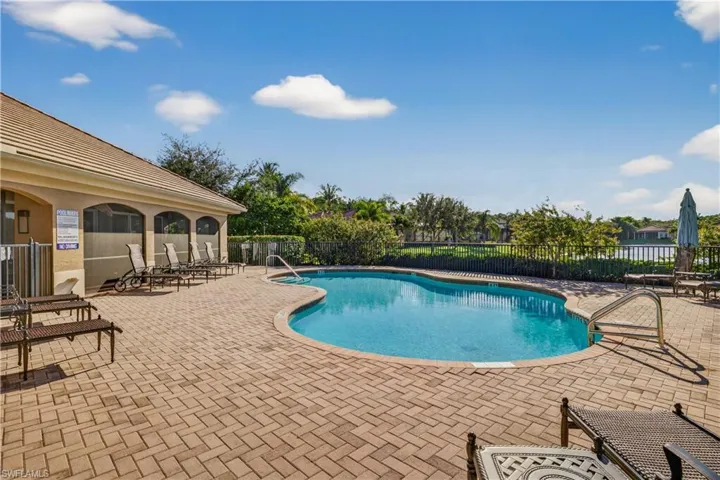 Black Bear Ridge Community Heated Pool Overlooking the Lake, Lounge Chairs, Umbrella's Rolling Out for Season, and Screened Lanais with Tables and Chairsfeaturing a patio area