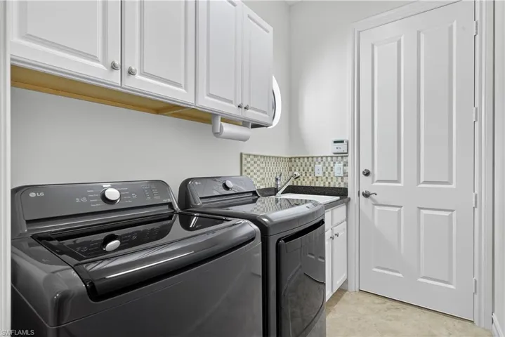 Laundry Room Featuring Additional Upper Cabinet Storage, Window, New LG Washer and Dryer, Laundry Tub, and Garage Entry