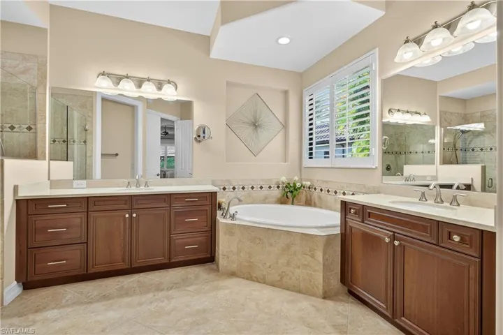 Full Primary Bathroom Ensuite with a Walk-In Glass Shower, Dual Vanities, a Soaking Tub, and Plantation Shutters