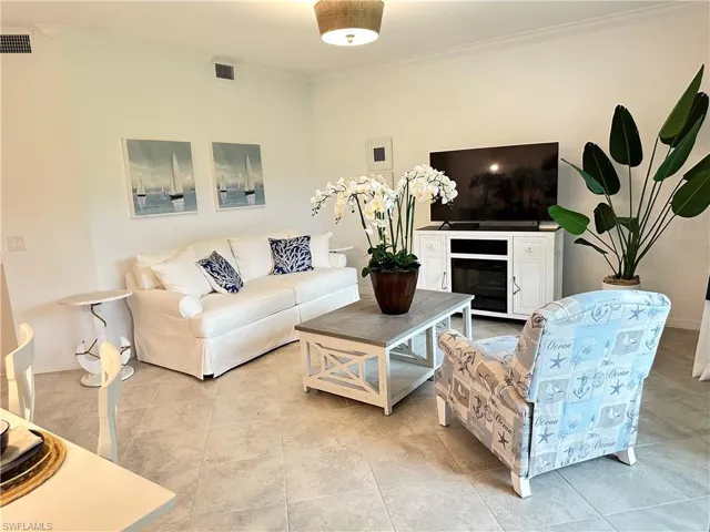 Living room featuring light tile patterned flooring and crown molding