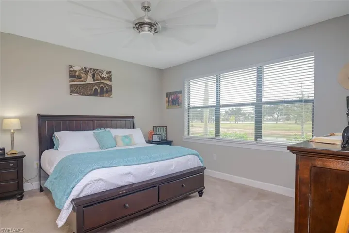 Carpeted bedroom with multiple windows and ceiling fan