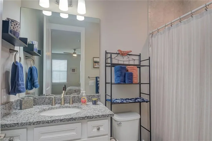 Bathroom featuring vanity, toilet, ceiling fan, and curtained shower