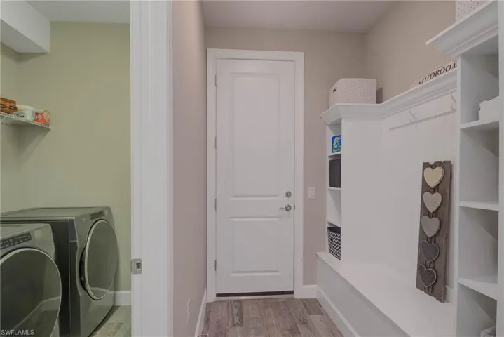 Clothes washing area featuring washer and dryer and light hardwood / wood-style floors