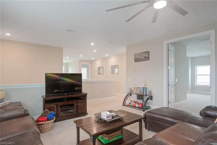 Carpeted living room with ceiling fan