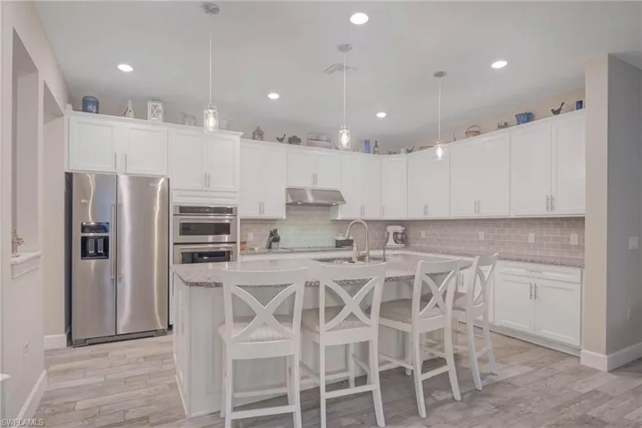 Kitchen with pendant lighting, white cabinetry, a kitchen island with sink, and appliances with stainless steel finishes