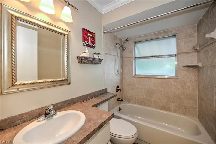 Full bathroom featuring tiled shower / bath, crown molding, toilet, and vanity