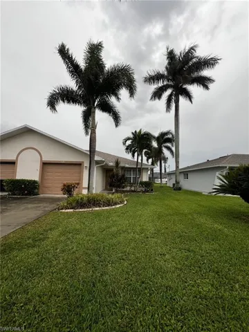 Ranch-style home with driveway, an attached garage, a front lawn, and stucco siding