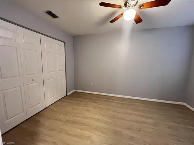 Unfurnished bedroom featuring light wood-style floors, a closet, and a ceiling fan