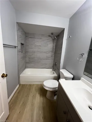 Bathroom featuring  shower combination, vanity, and light wood-style floors