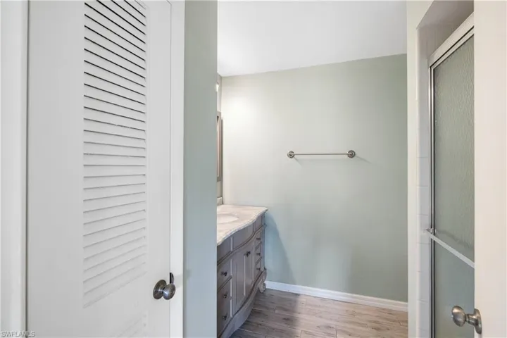 Primary bathroom with a walk in shower to the right, vanity and commode straight  ahead