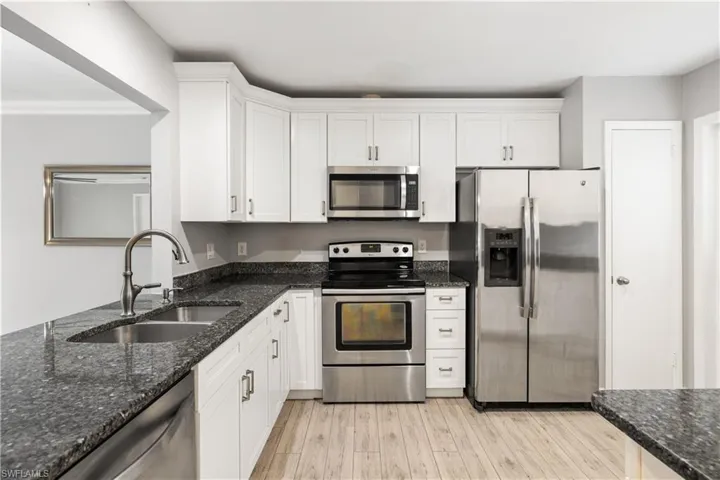 Kitchen featuring white soft-close shaker cabinets, stainless appliances and granite countertops