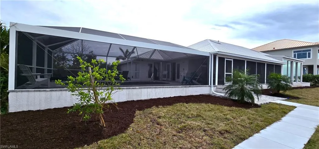 Rear view of property with a lanai, and a lawn