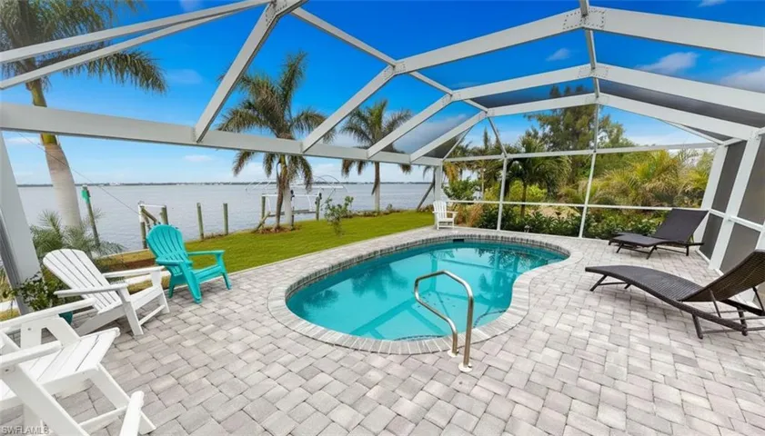 Swimming pool with a patio, glass enclosure, a water view, and a sunroom