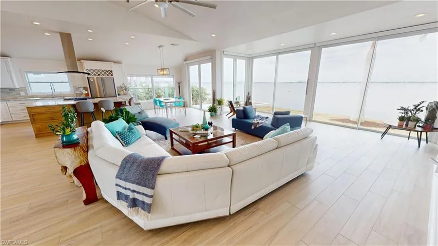 Living area with a water view, tile floors, recessed lighting, high vaulted ceiling, and a ceiling fan