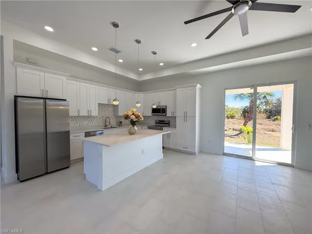 Kitchen featuring stainless steel appliances, white cabinets, hanging light fixtures, and a kitchen island