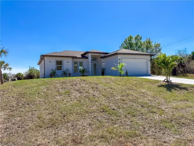 View of front of property with a front yard, stucco siding, an attached garage, and concrete driveway